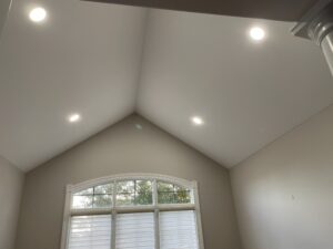 Vaulted ceiling with recessed smart lighting and arched window in a modern home interior